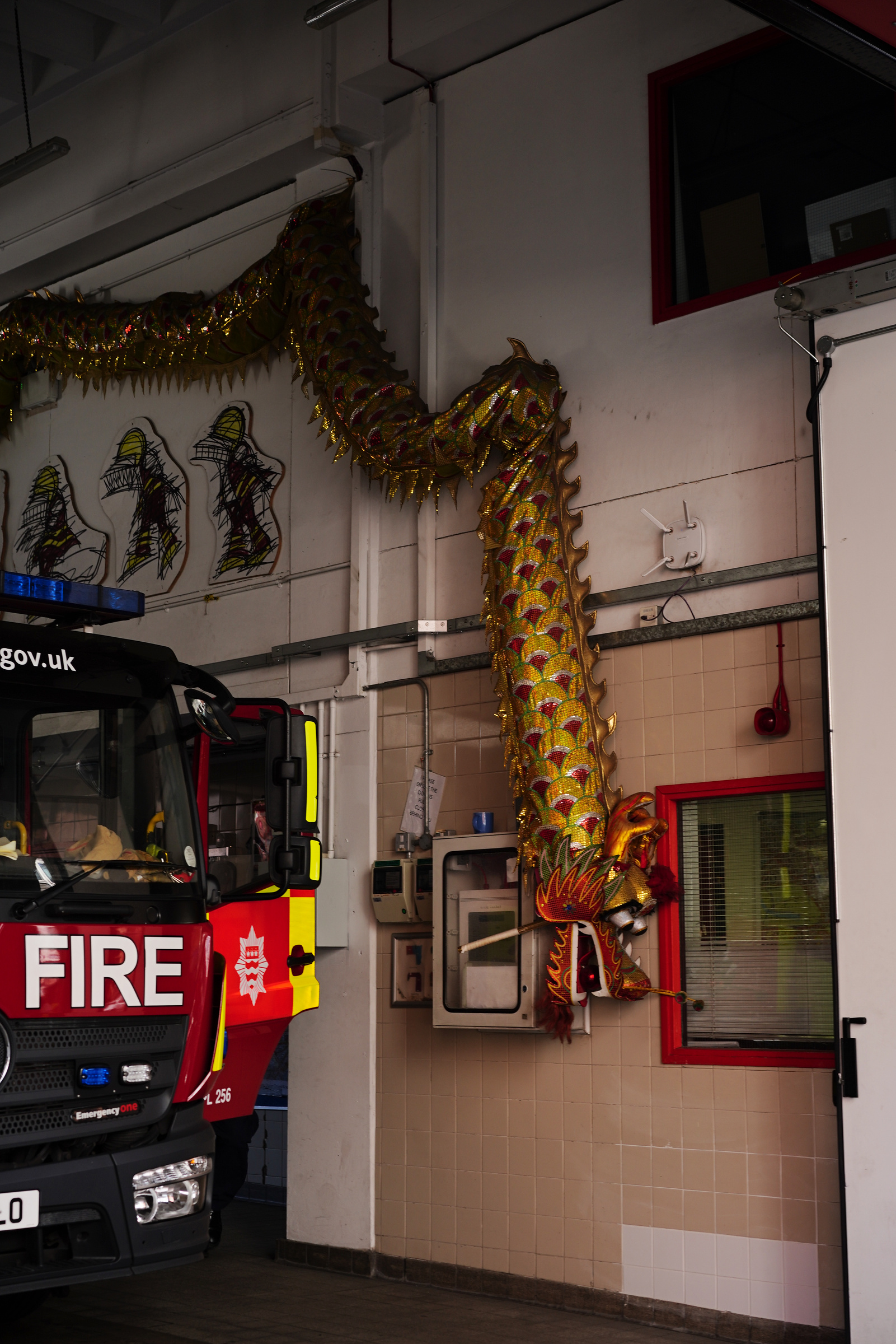 A golden dragon hangs head-down beside a fire engine.
