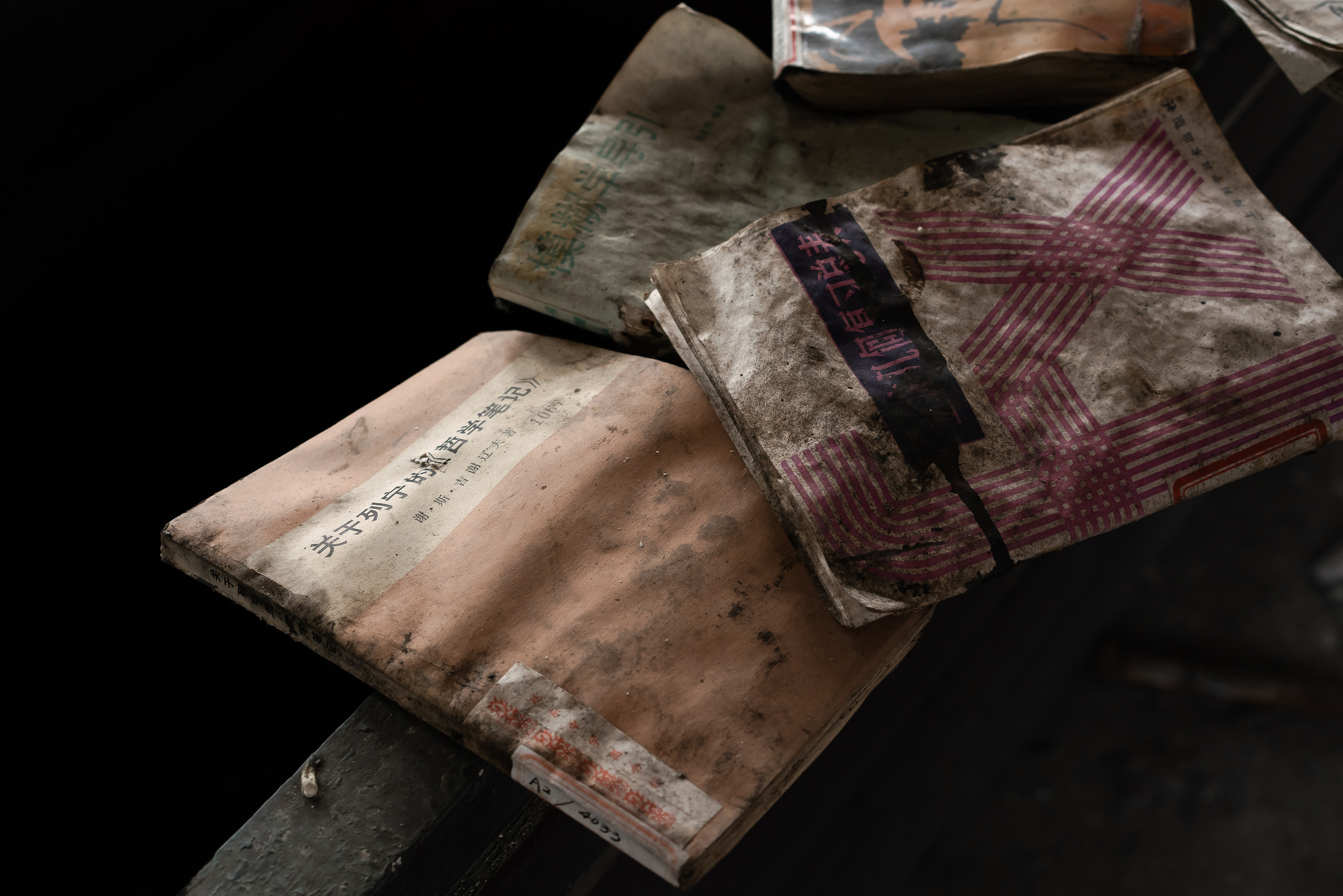 Dust-covered books overlap diagonally in a dark interior.