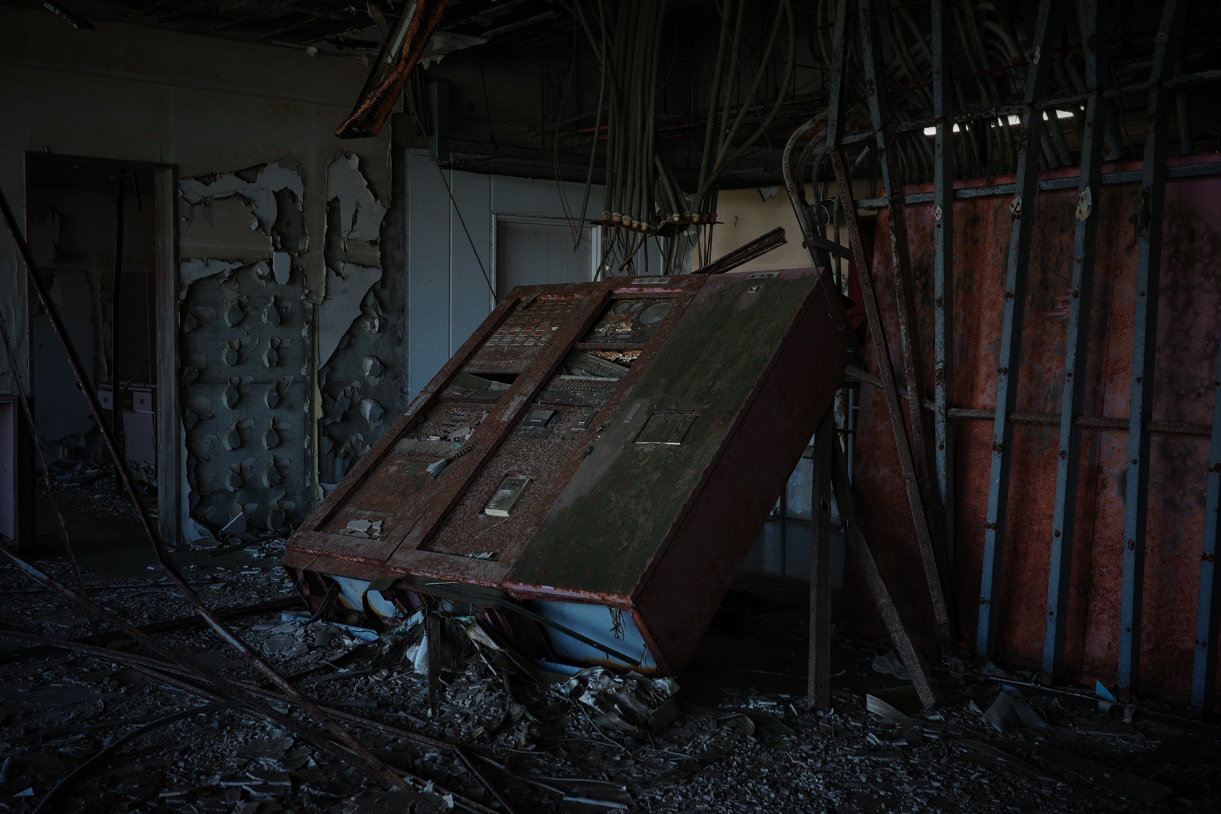 A tilted instrument cabinet stands amid exposed wires and damaged walls.