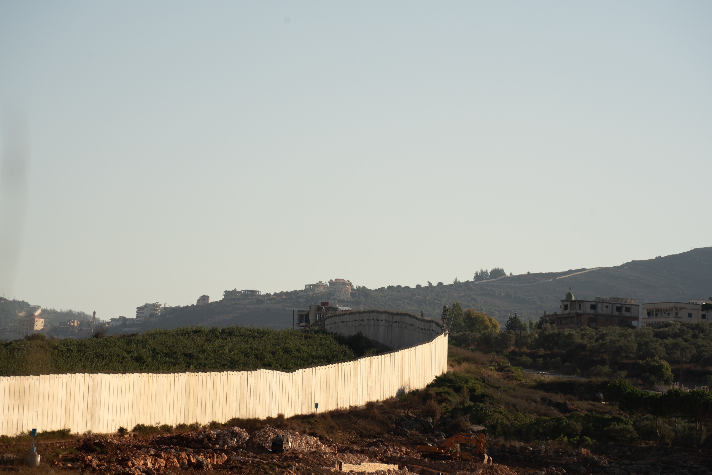 A pale wall curves across a hillside landscape.