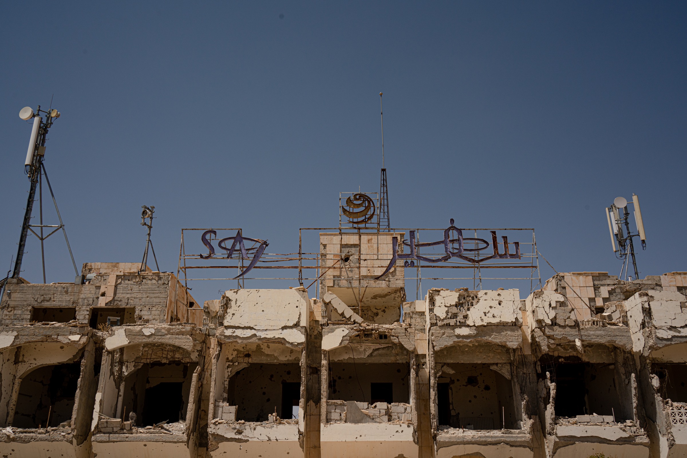 Signs and antennas remain above the damaged facade of a building.